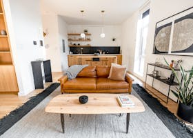 Stylish modern living room with a leather sofa, kitchen area, and decor elements.